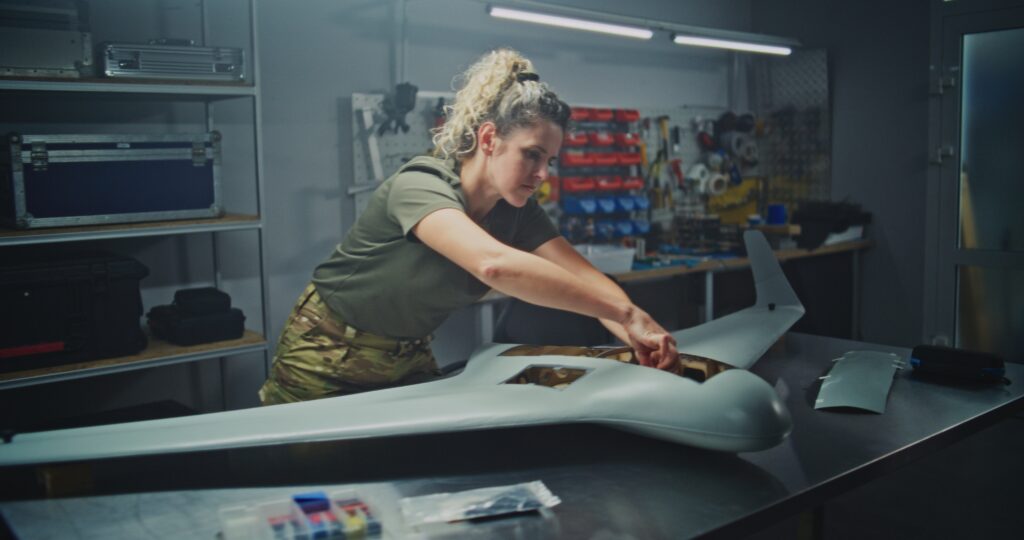 Technician assembling a military-style unmanned aircraft in a workshop, representing engineering plastics and composites for military drone, defense UAV, and unmanned aircraft components.