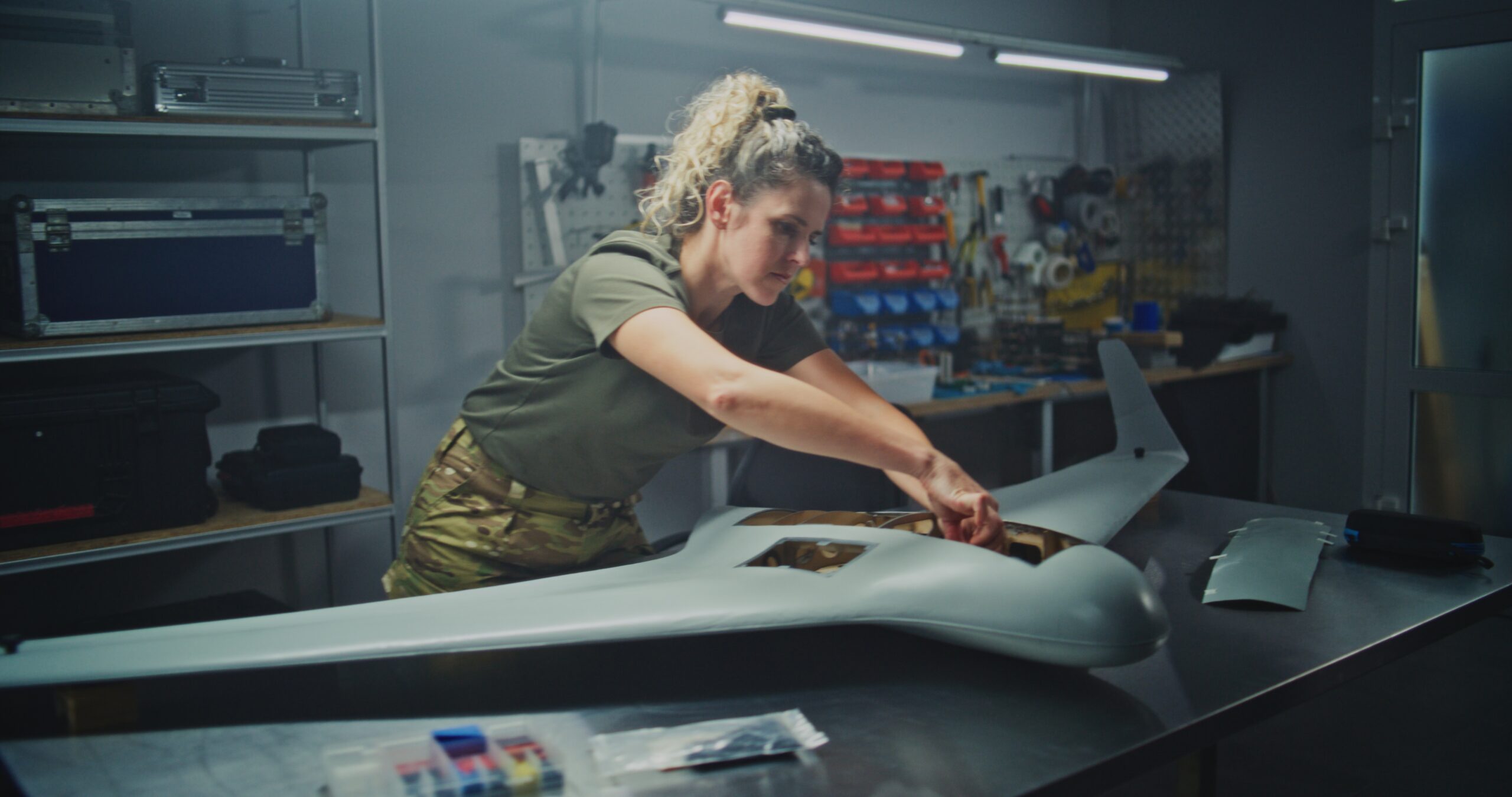 Technician assembling a military-style unmanned aircraft in a workshop, representing engineering plastics and composites for military drone, defense UAV, and unmanned aircraft components.